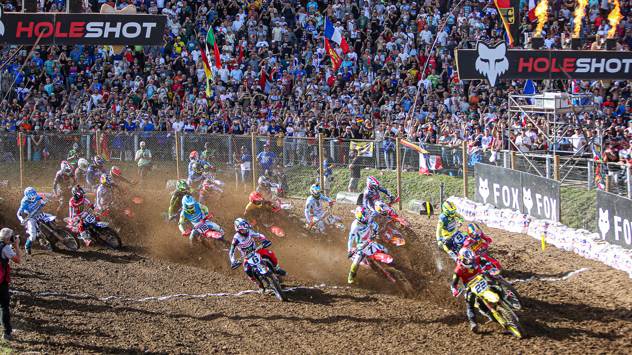 A group of riders on motorcycles on a dirt track, at the mx of nations.