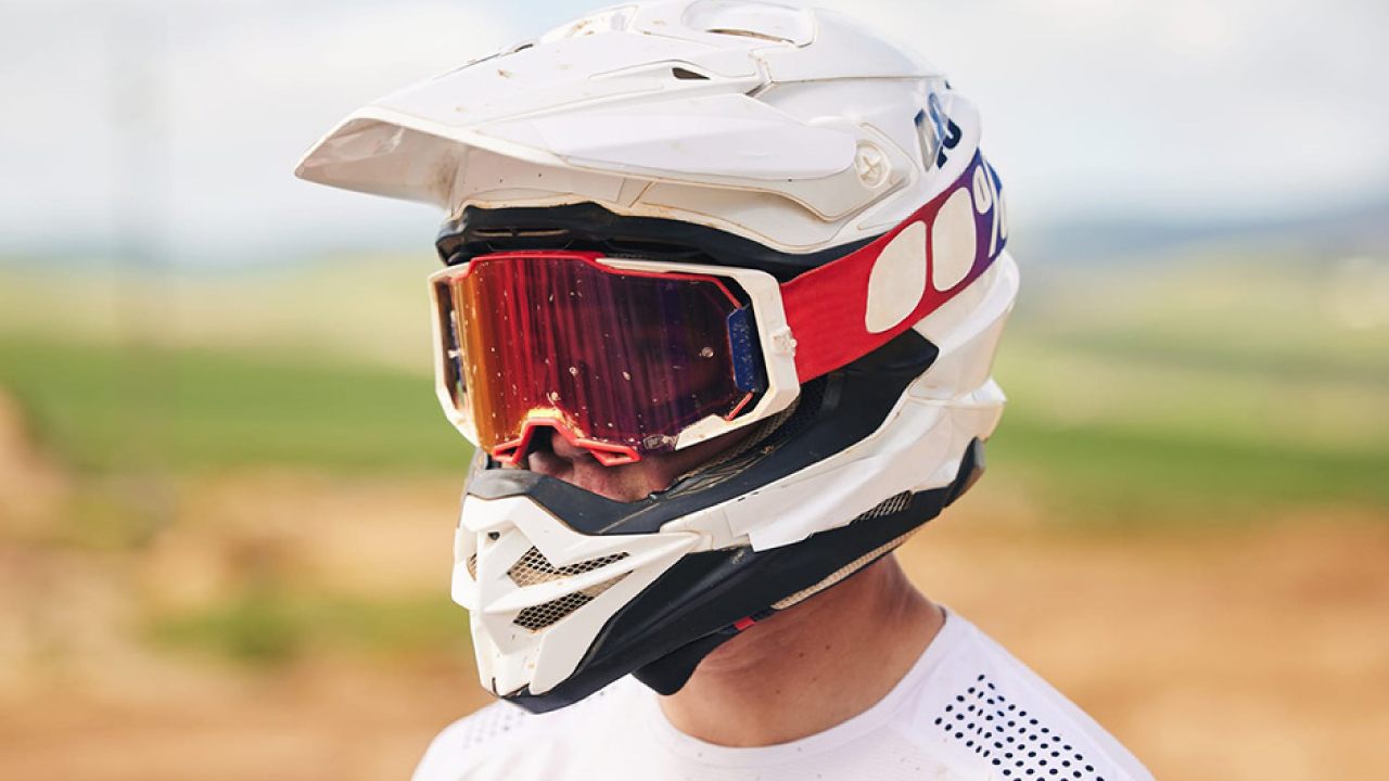 A man wearing a helmet and goggles speeds along a dirt road, featuring the best motocross helmets of 2024.